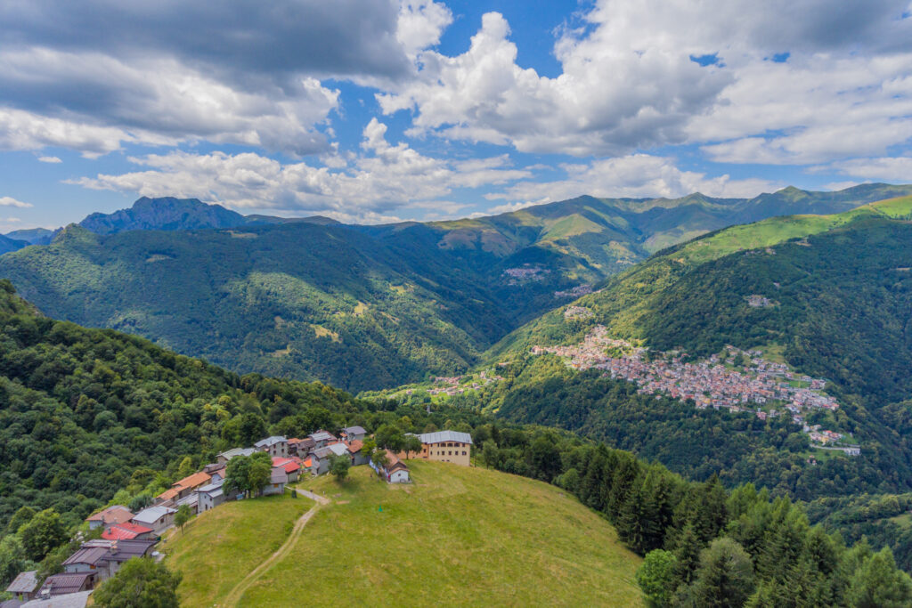 La vallata verdeggiante con il profilo del paese che domina l'accesso alla Val Cavargna