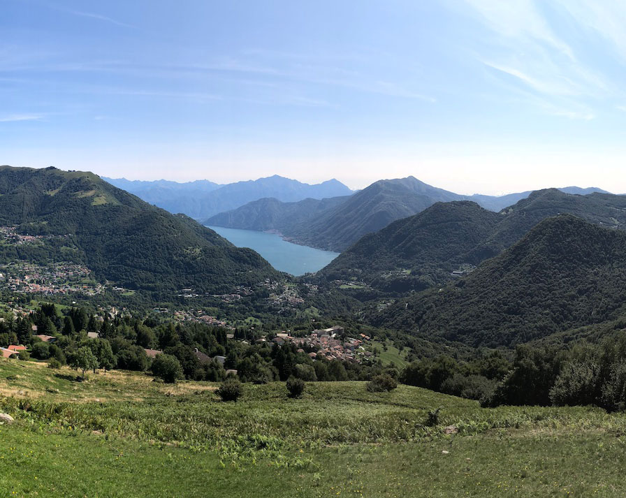 Uno scorcio panoramico dei prati verdi della Conca di San Fedele con le cime delle montagne sullo sfondo